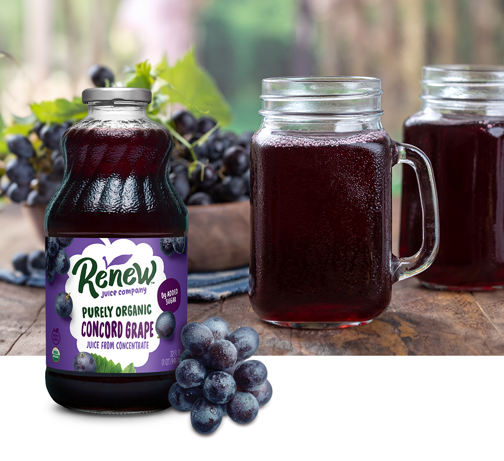 Bottle of Renew Purely Organic Concord Grape Juice with a group of grapes sitting in front of the bottle and an image of a mug of grape juice sitting on a wood surface.